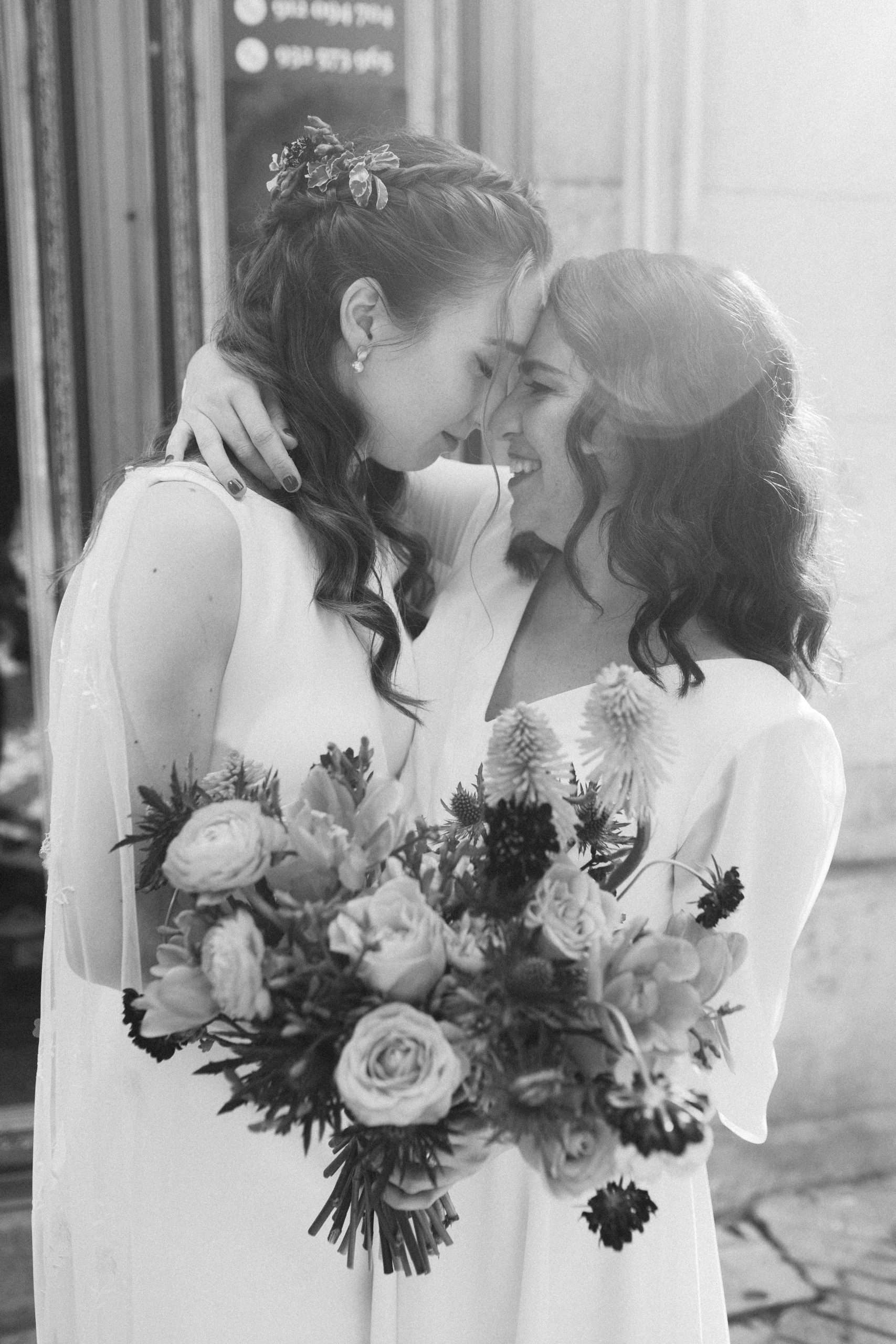 two brides holding each other with bouquet of flowers