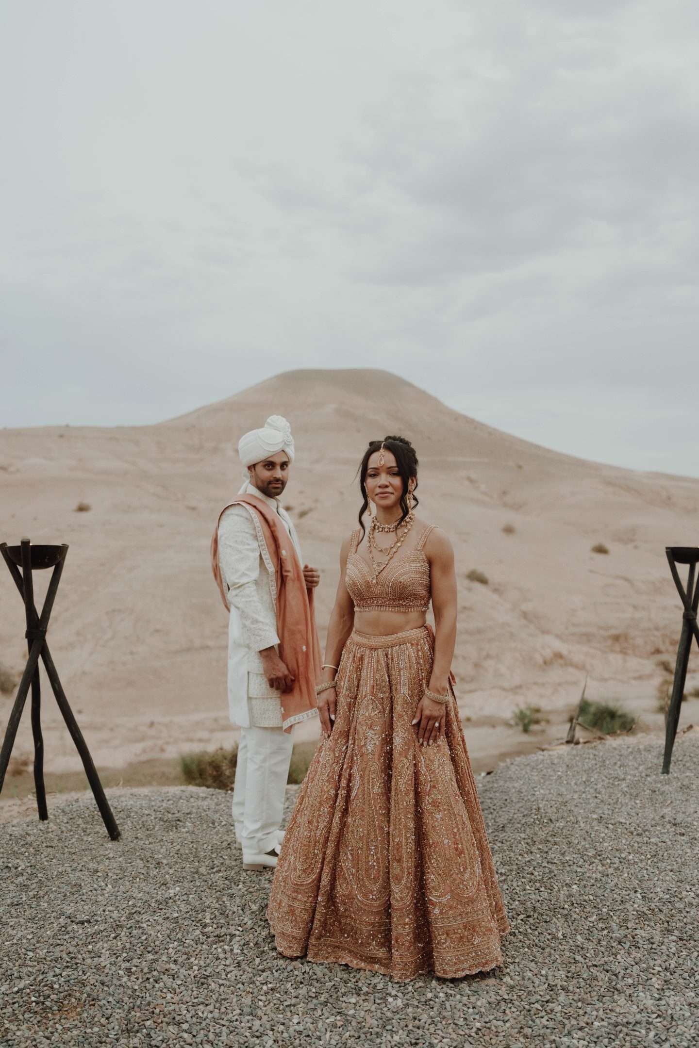 Bride and groom in indian attire posing in front of desert mountain in marrakesh